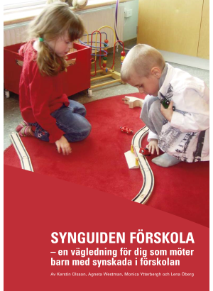 Två barn leker på golvet inne på en förskola.